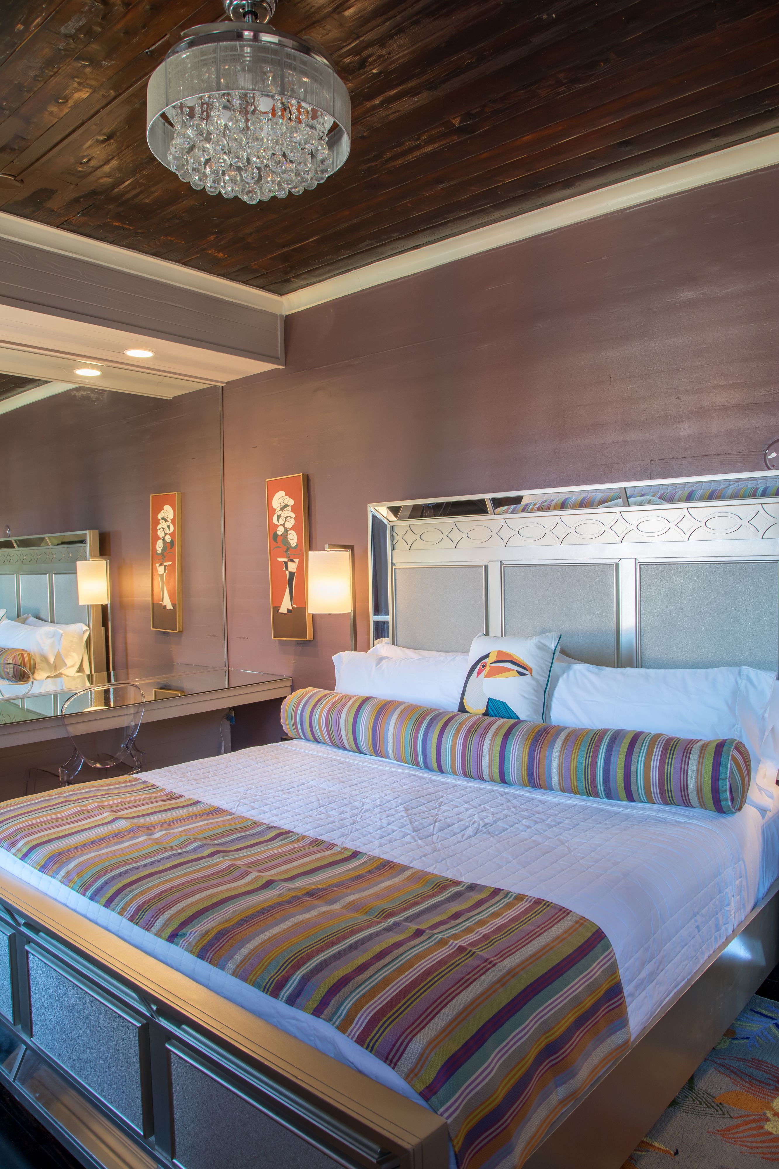 Quarto de hotel com uma cama grande, teto de madeira e um lustre.