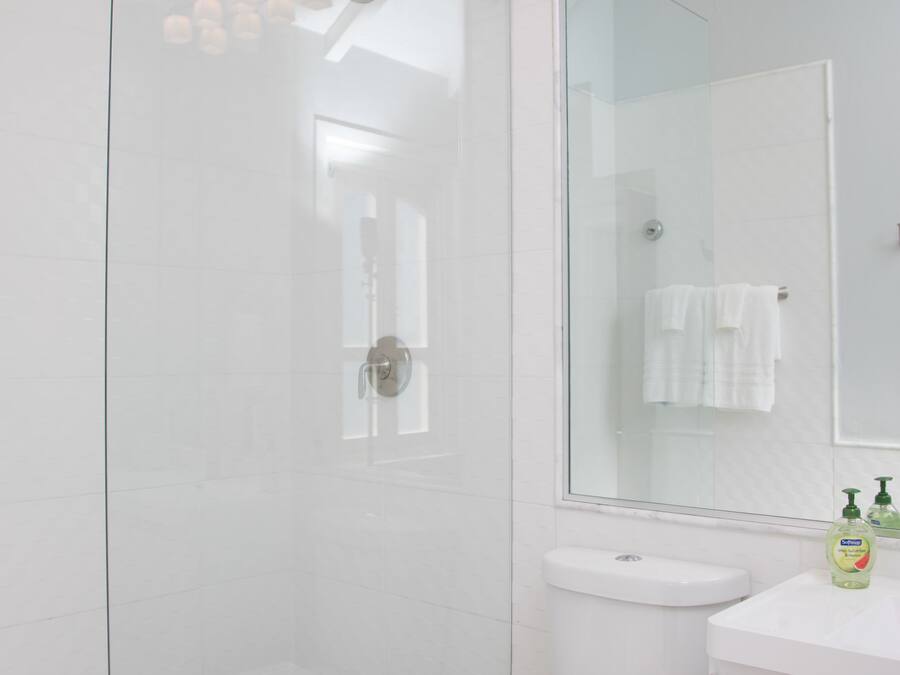 A modern bathroom with a glass shower enclosure, a white toilet, and a vanity with a mirror.