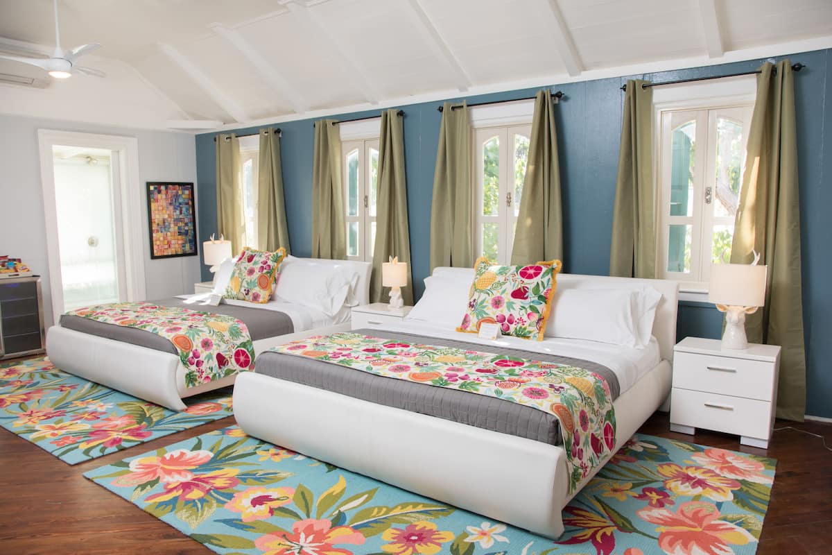A bedroom with two beds, a nightstand, a ceiling fan, and a window with curtains.