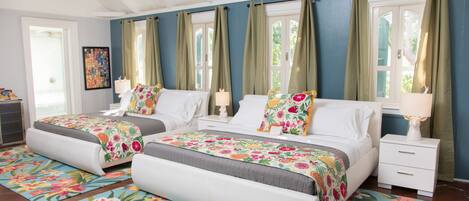 A bedroom with two beds, a nightstand, a ceiling fan, and a window with curtains.