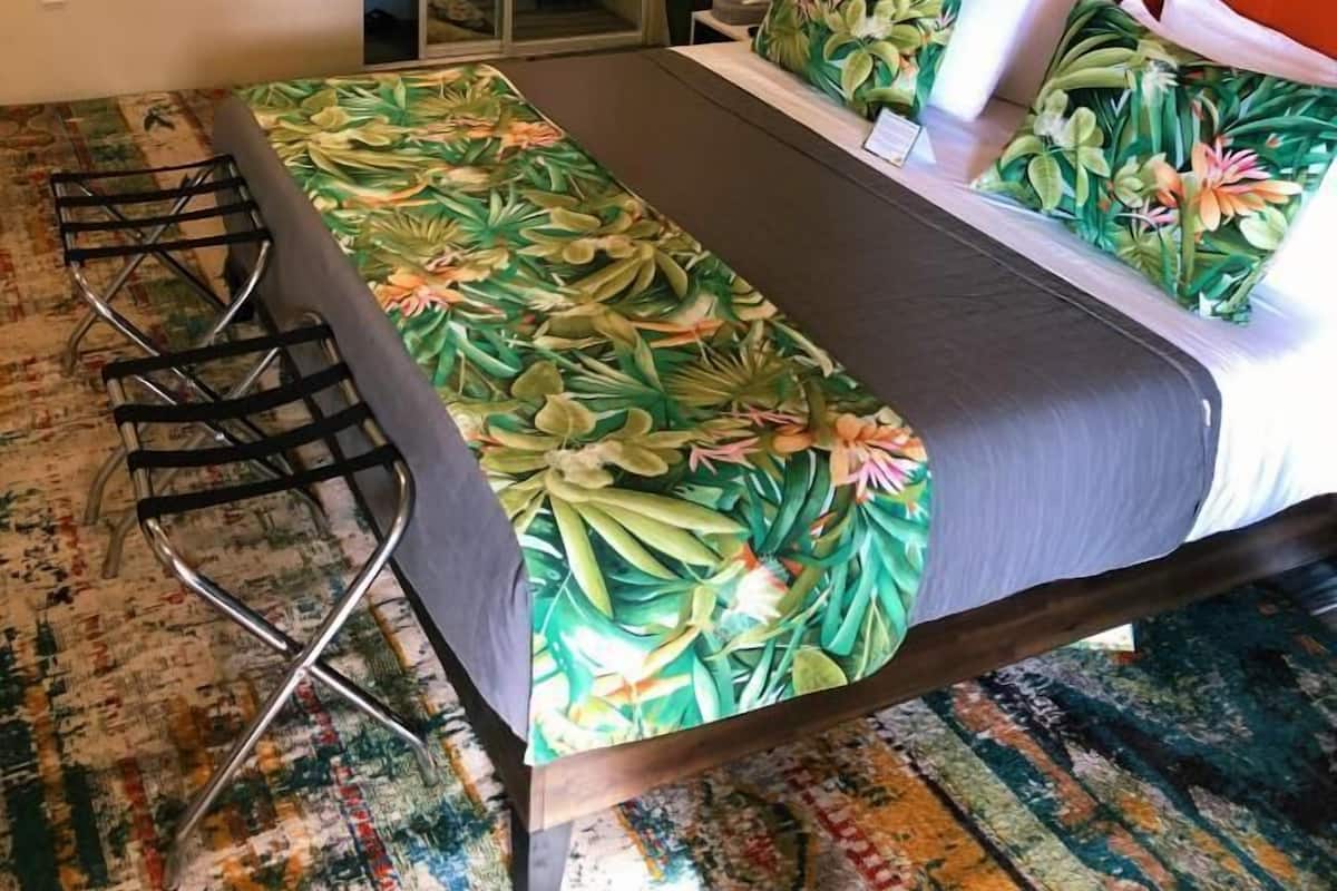 A bedroom with a bed, a chair, a mirror, and an air conditioning unit.