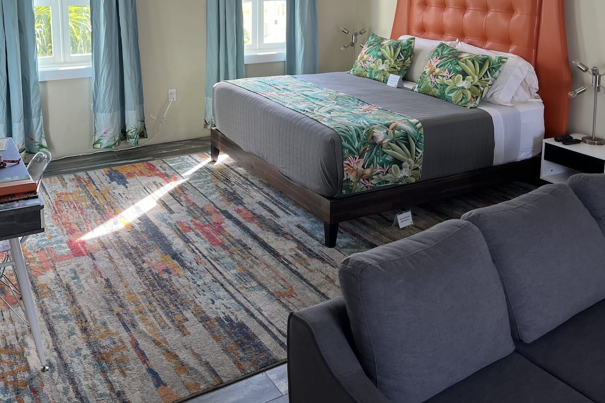 A bedroom with a bed, a ceiling fan, a nightstand, and a window with curtains.