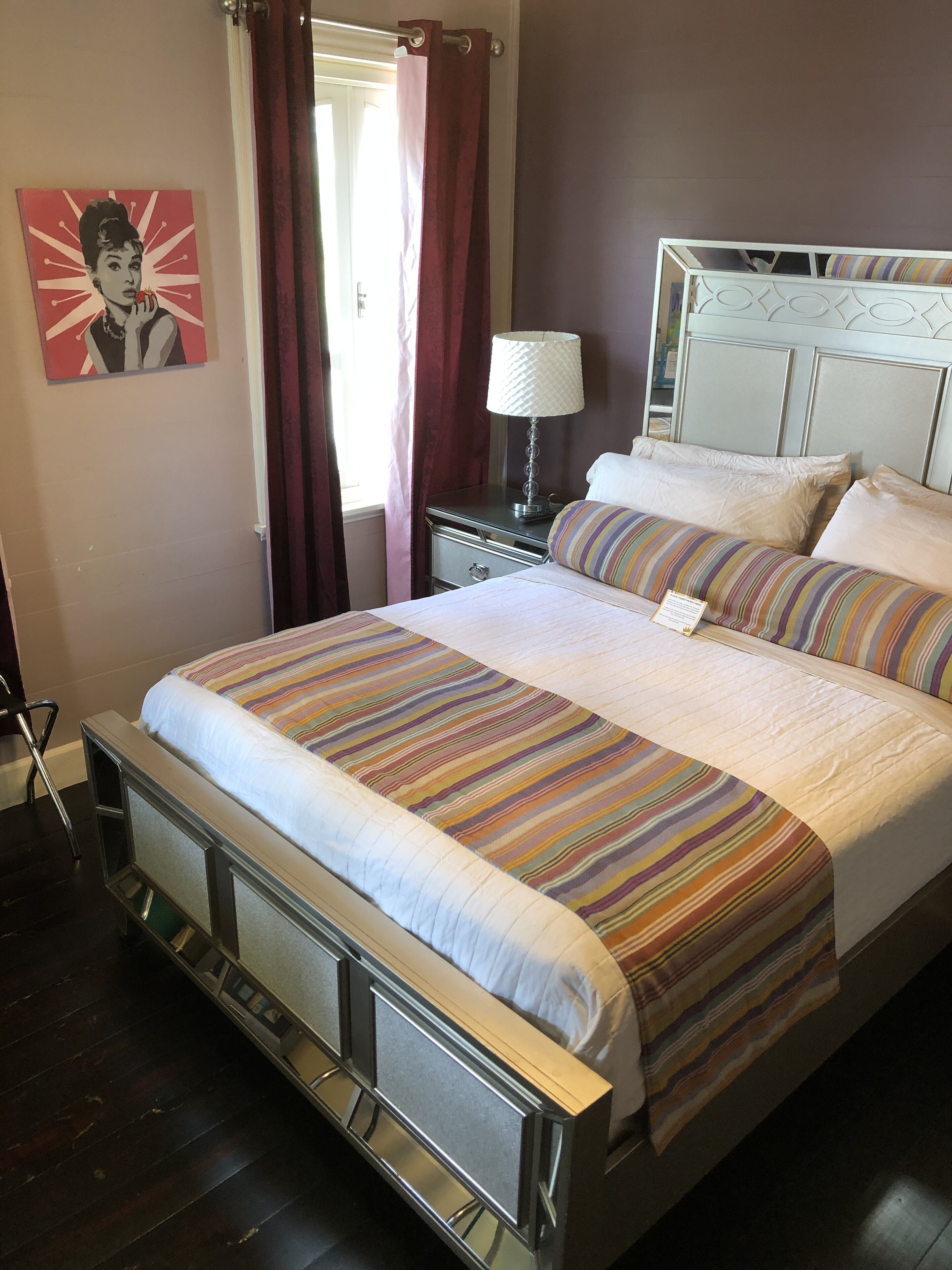 A neatly made bed with striped bedding, a bedside lamp, and a headboard with a decorative pattern.