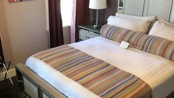 A neatly made bed with striped bedding, a bedside lamp, and a headboard with a decorative pattern.