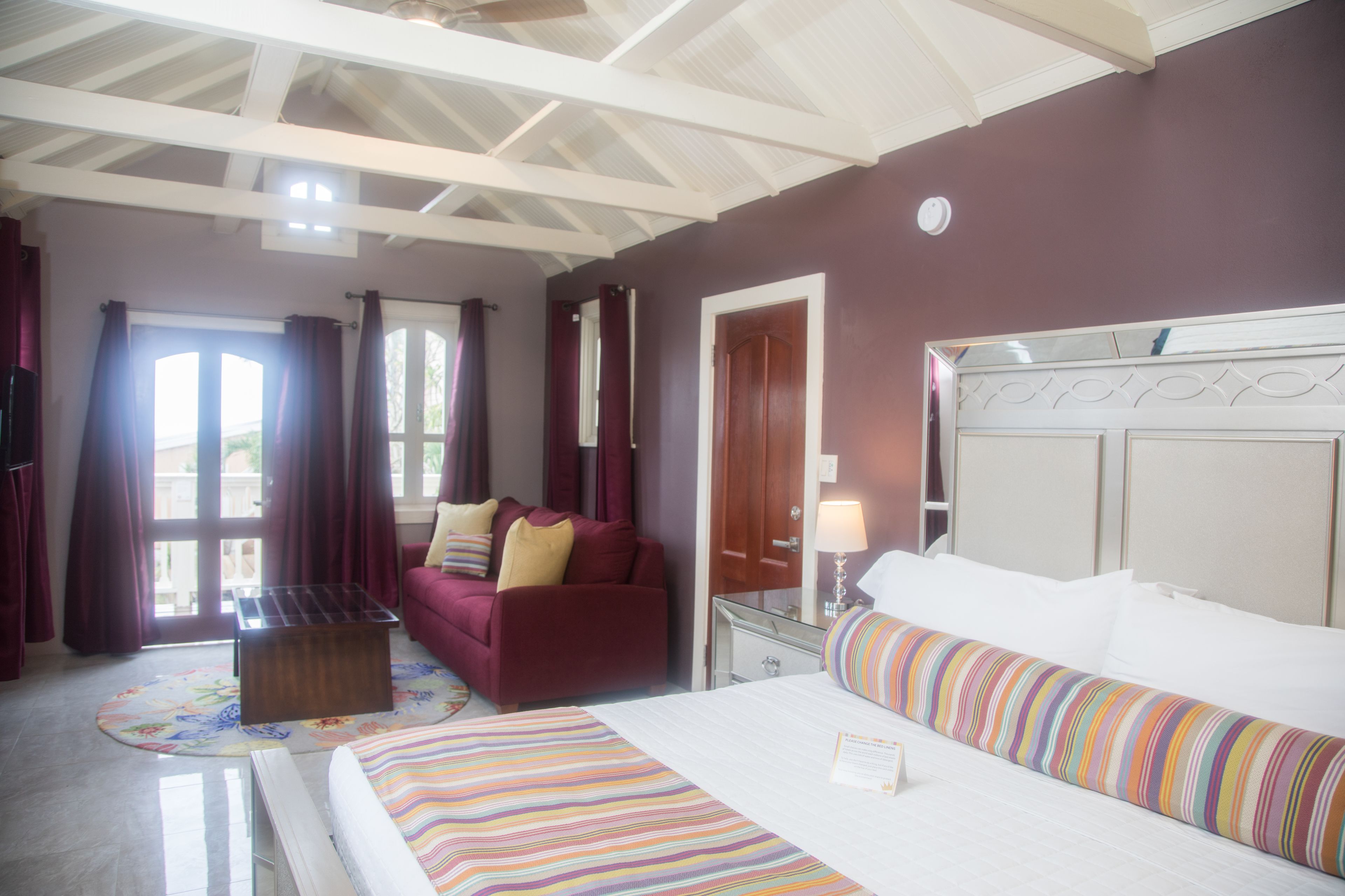 A hotel room with a bed, a sofa, a desk, and a window with curtains.