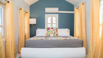 A bedroom with a bed, curtains, a window, and an air conditioning unit.