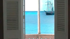 An open doorway leading to a balcony with a view of the sea and a ship. - The Fred - Adults Only (Frederiksted)