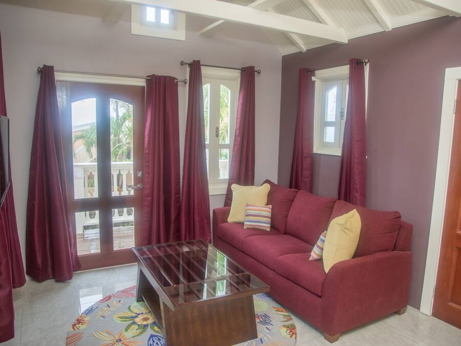A living room with a red sofa, a glass coffee table, and a TV on the left.