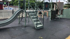 Un parque infantil con un tobogán, escaleras y una estructura para escalar.