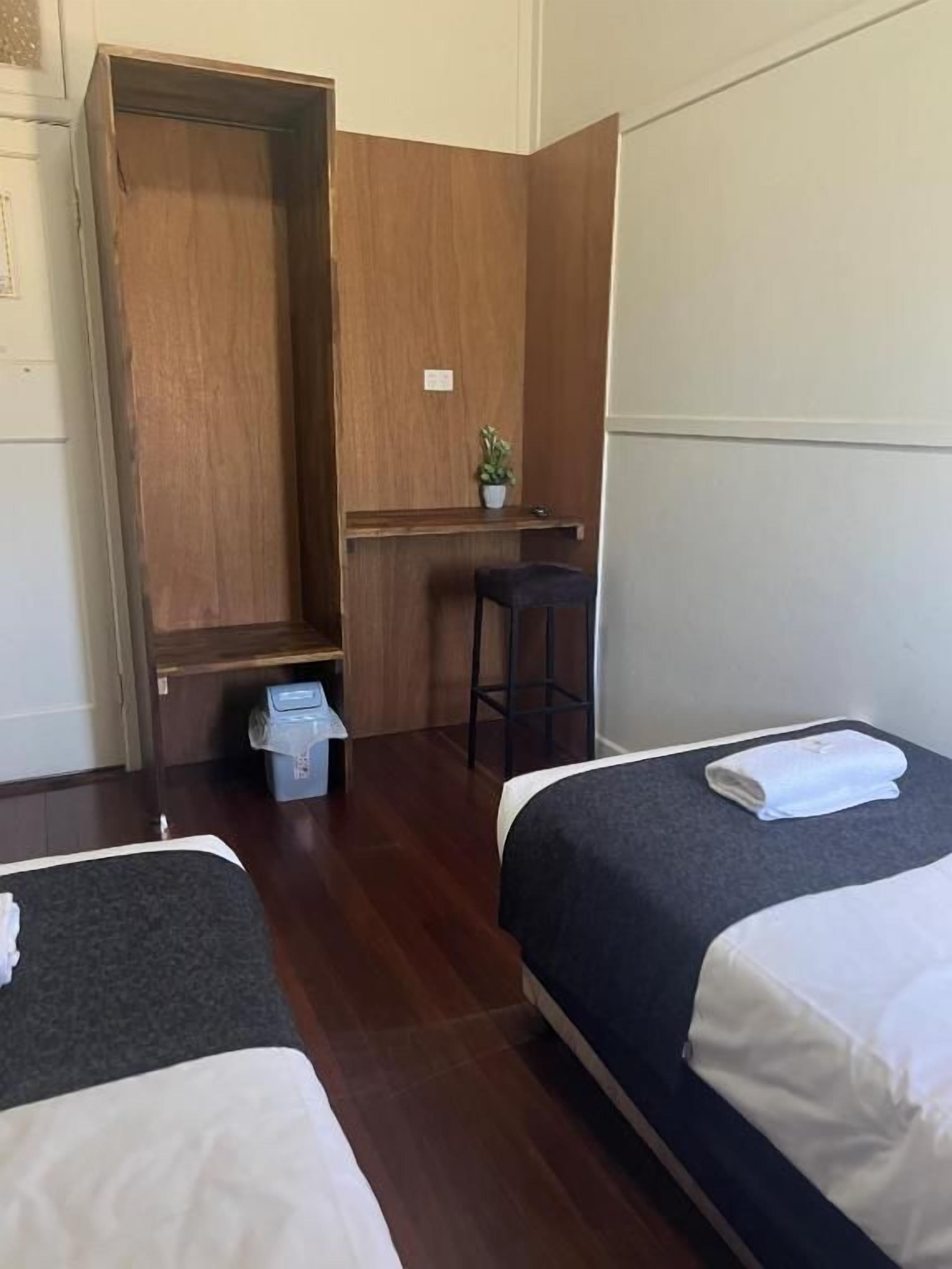 A hotel room with two beds, a desk, a chair, and a wardrobe.