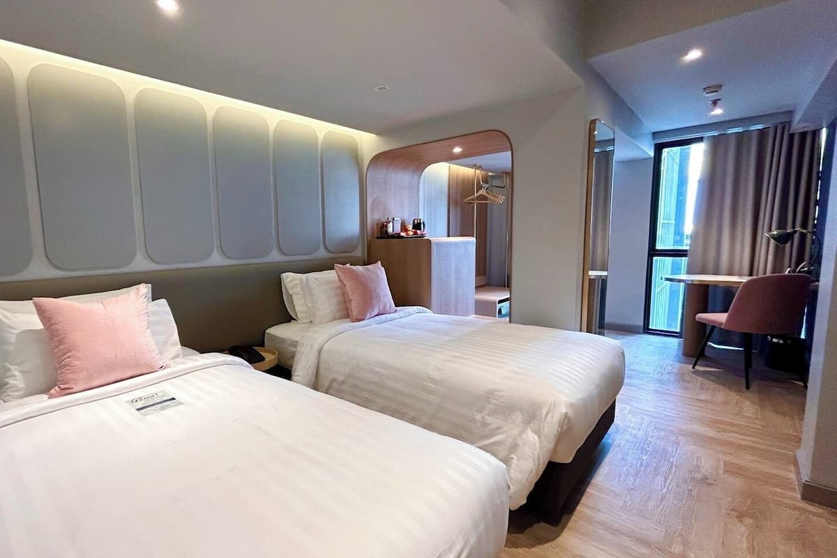 Een hotelkamer met twee bedden, een bureau en een stoel.