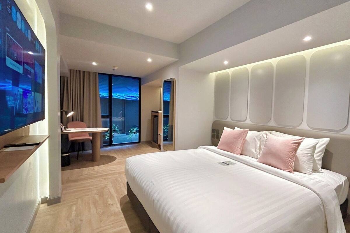 Een moderne hotelkamer met een groot bed, een bureau en een televisie.