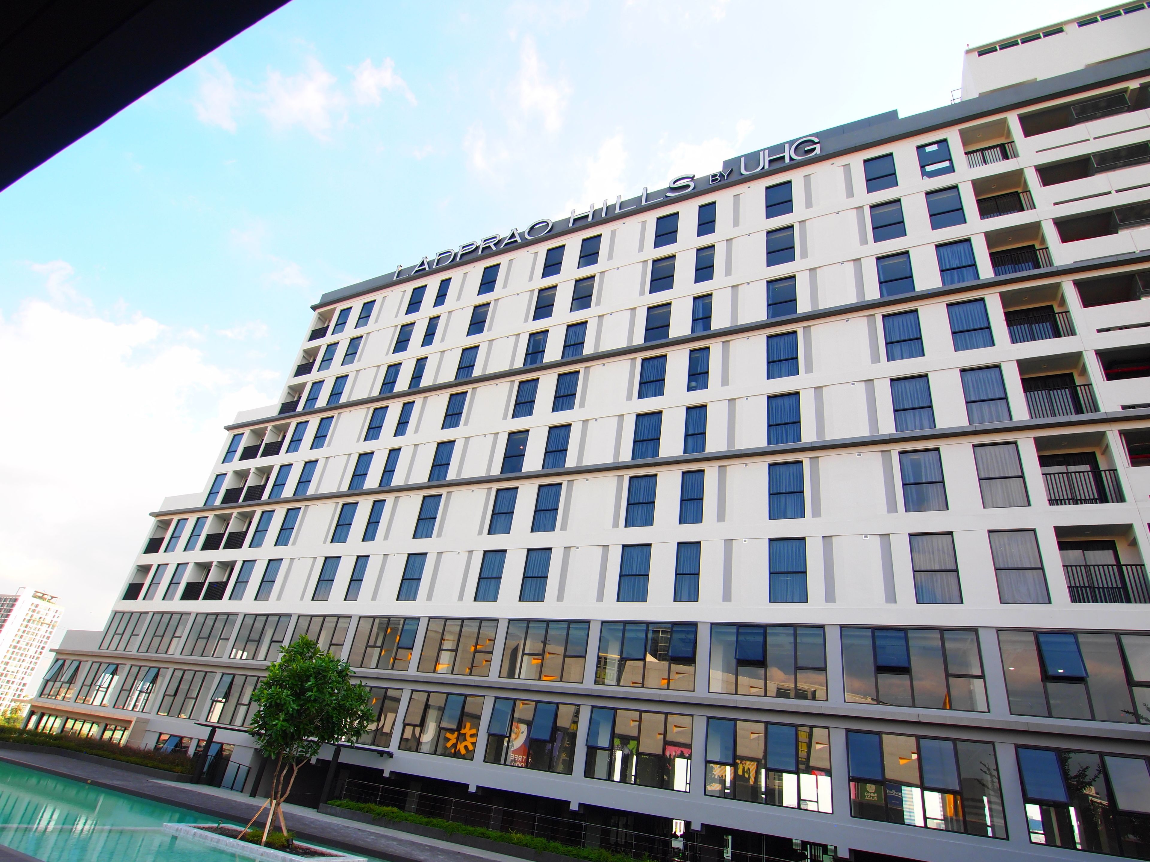 A multi-story hotel with a modern facade, large windows, and a visible pool area.