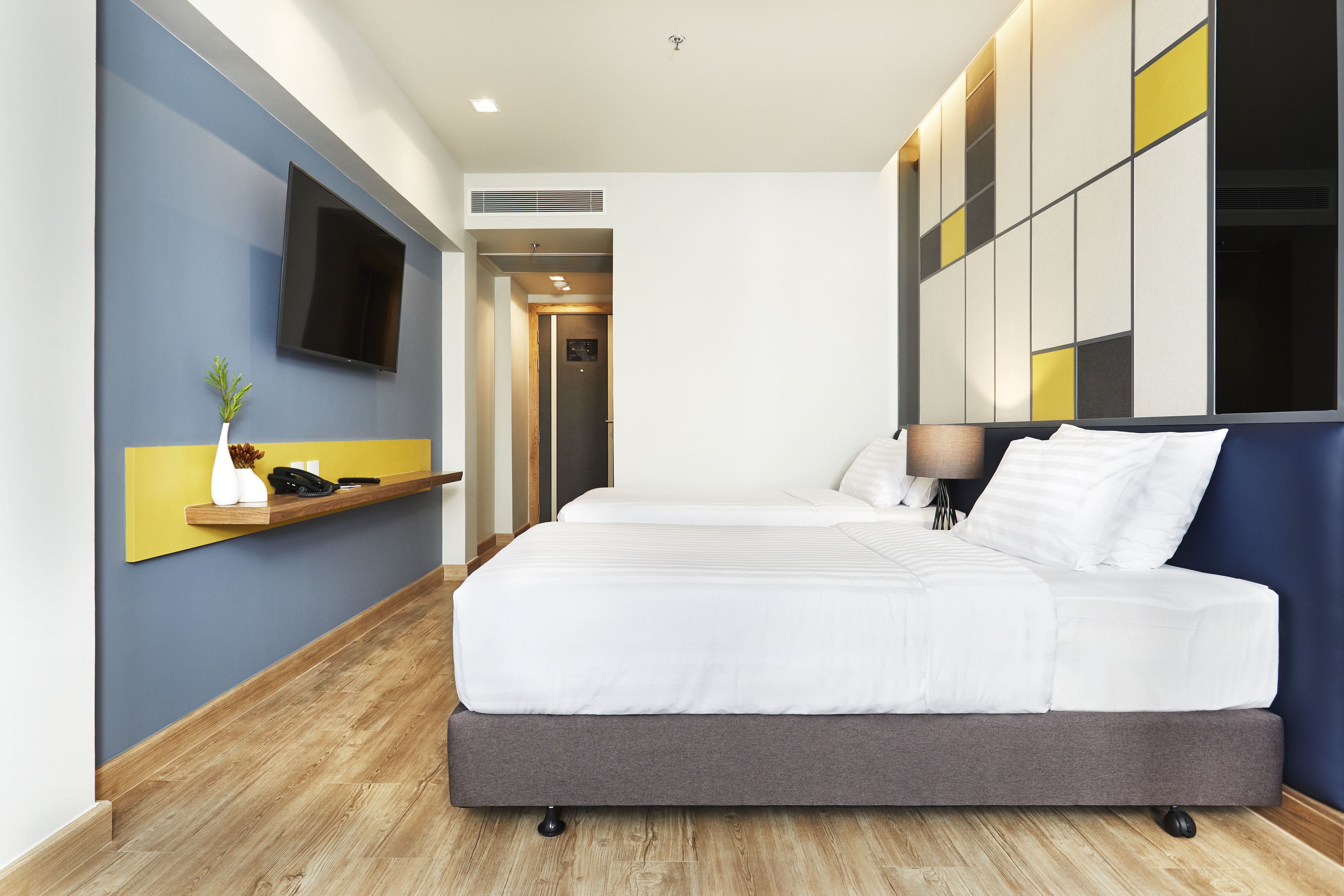 Una habitación de hotel con una cama grande, un televisor de pantalla plana montado en la pared y piso de madera.