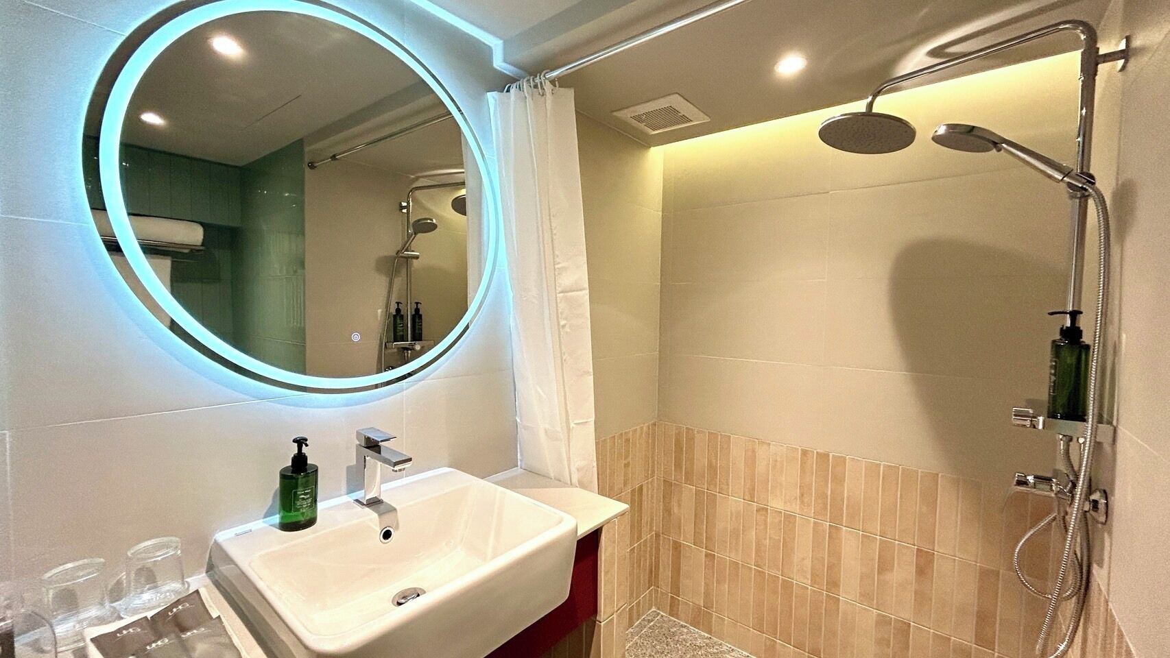 Un baño con un espejo redondo, un lavabo y una ducha.