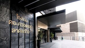 A modern building entrance with a marble wall and a sign in a foreign language.