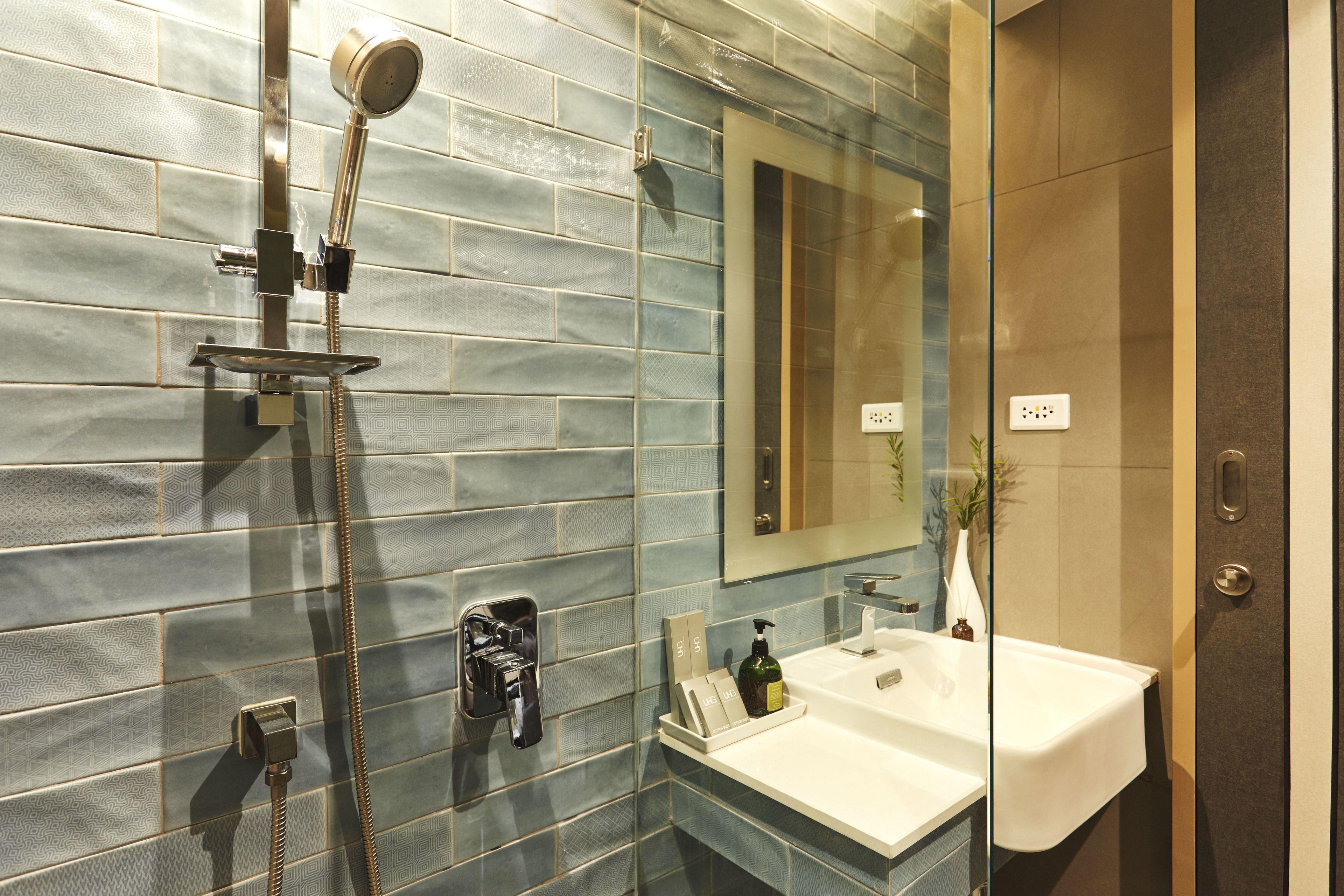 A modern bathroom with a glass shower enclosure, a white sink, and a mirror above the sink.