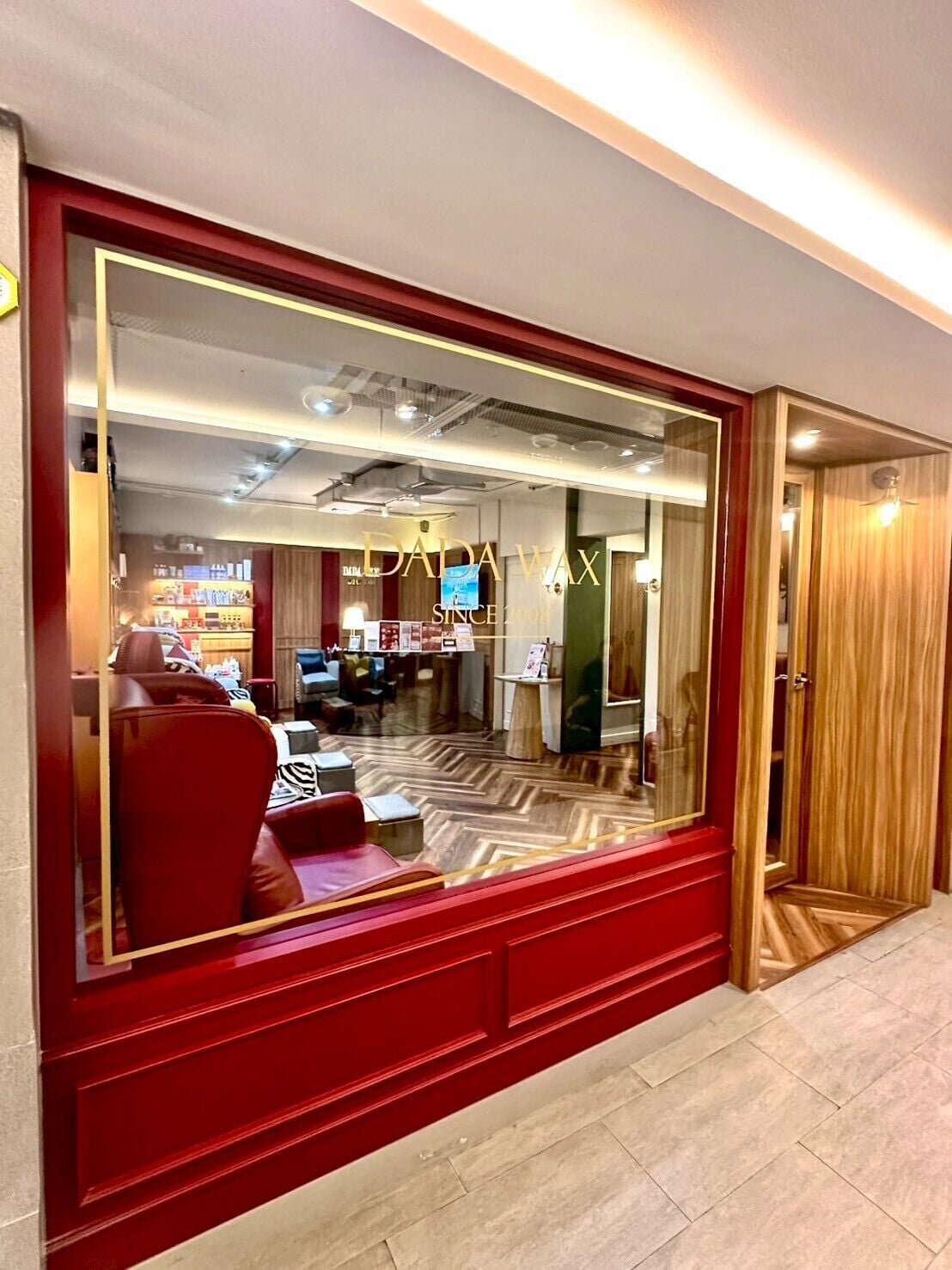 Un interior modern amb una decoració vermella i daurada, que inclou una zona de seients amb cadires vermelles i un paviment amb motius de guilló.