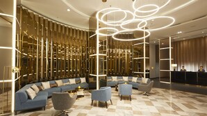 A modern lobby with a curved seating area, a reception desk, and a decorative light installation.