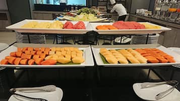 Un bufé con diversos alimentos, entre ellos frutas, verduras y carne.