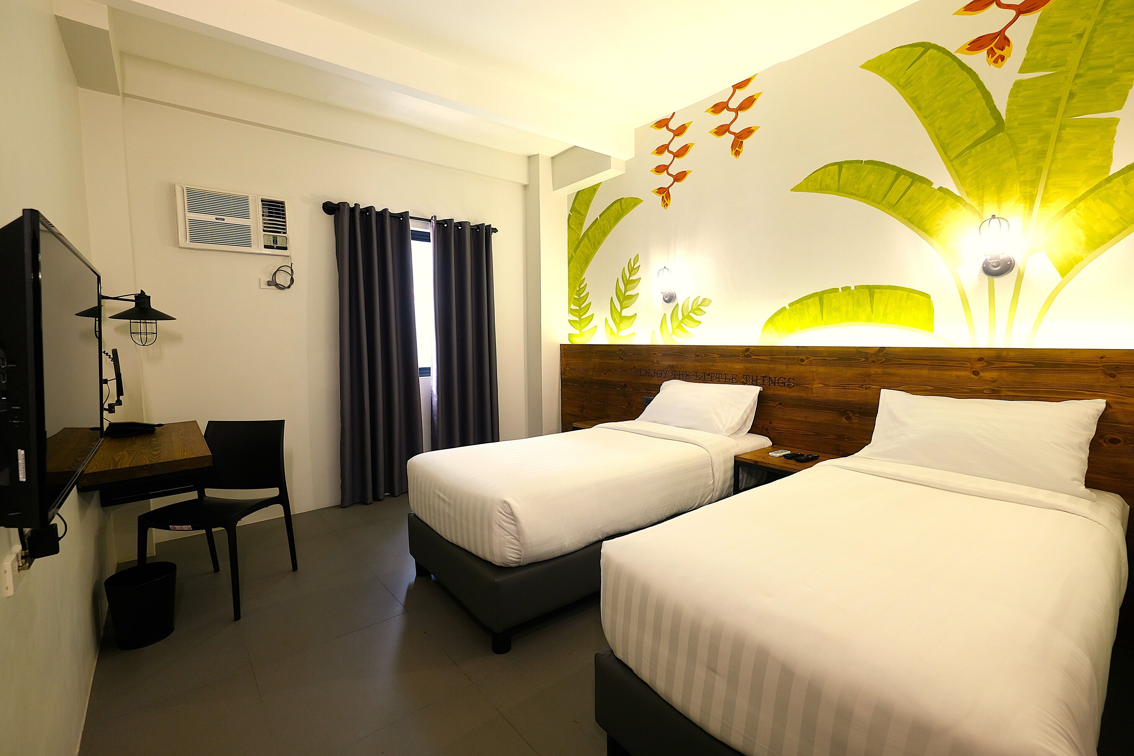 A hotel room with two beds, a desk, a chair, and a television.