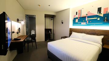 Hotelkamer met een bed, bureau, stoel, televisie, badkamer en een kunstwerk aan de muur.