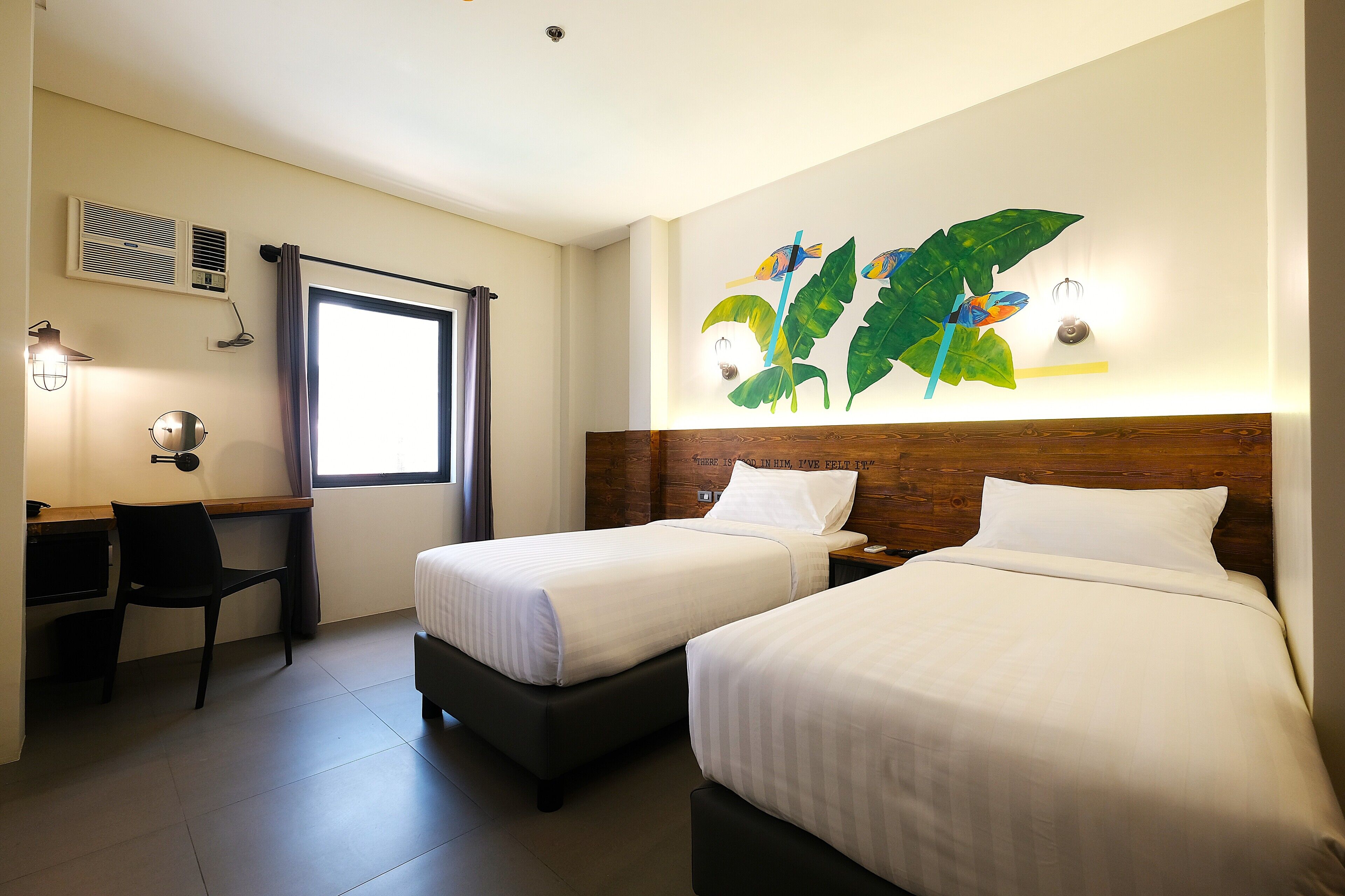 A hotel room with two beds, a desk, a chair, and a large window.