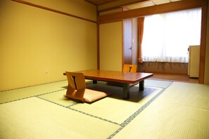 A traditional Japanese room with tatami flooring, a low table, and a wooden chair.