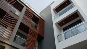 Um edifício moderno com várias varandas, grandes janelas e uma combinação de elementos de madeira e vidro.