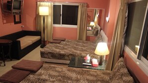 A hotel room with a bed, a sofa, a small table, and a window with curtains. - Rim Khuan Resort (Khuan Khanun)