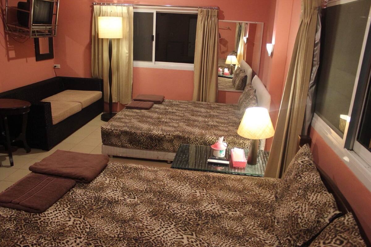 A hotel room with a bed, a sofa, a small table, and a window with curtains.