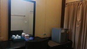 A hotel room with a large mirror, a small refrigerator, a desk with a chair, and a curtain. - Rim Khuan Resort (Khuan Khanun)