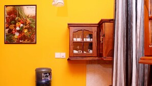 A compact kitchen with a water dispenser, a sink, wooden cabinets, and a blue rug. - The cool nest yala hotel (Thissamaharama)