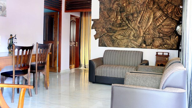 A living room with a sofa, chairs, and a large decorative wall piece. - The cool nest yala hotel (Thissamaharama)