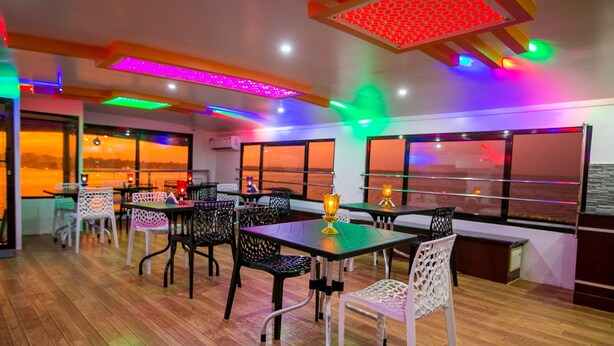 Un restaurante con suelo de madera, mesas con sillas y ventanas amplias con vistas.