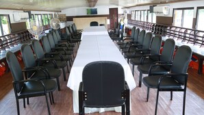 Un salón de conferencias con una larga mesa, filas de sillas y suelo de madera.