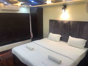 A hotel room with a large bed, a wardrobe, and a ceiling fan. - Jct Houseboats (Ambalapuzha)
