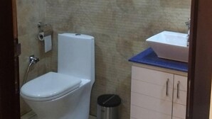 Un baño con inodoro, lavamanos y cubo de basura.