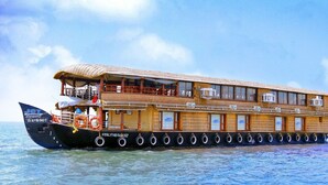 Una amplia casa flotante de madera con varias terrazas, unidades de aire acondicionado y techo de paja.