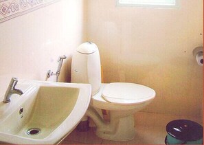A bathroom with a sink, toilet, and trash bin. - Jct Houseboats (Ambalapuzha)