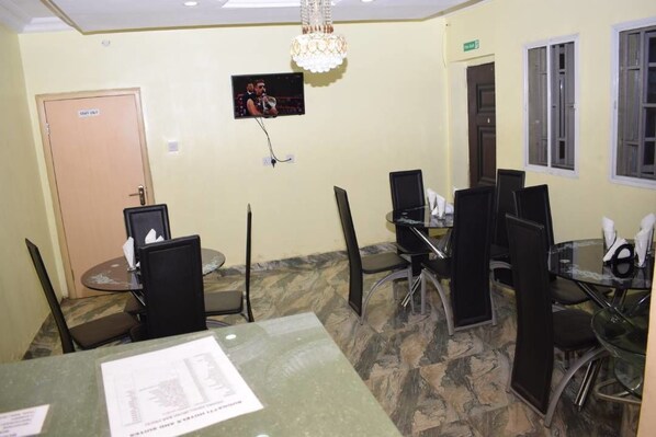A conference room with a television mounted on the wall, a chandelier, and a door labeled "STAY ONLY".