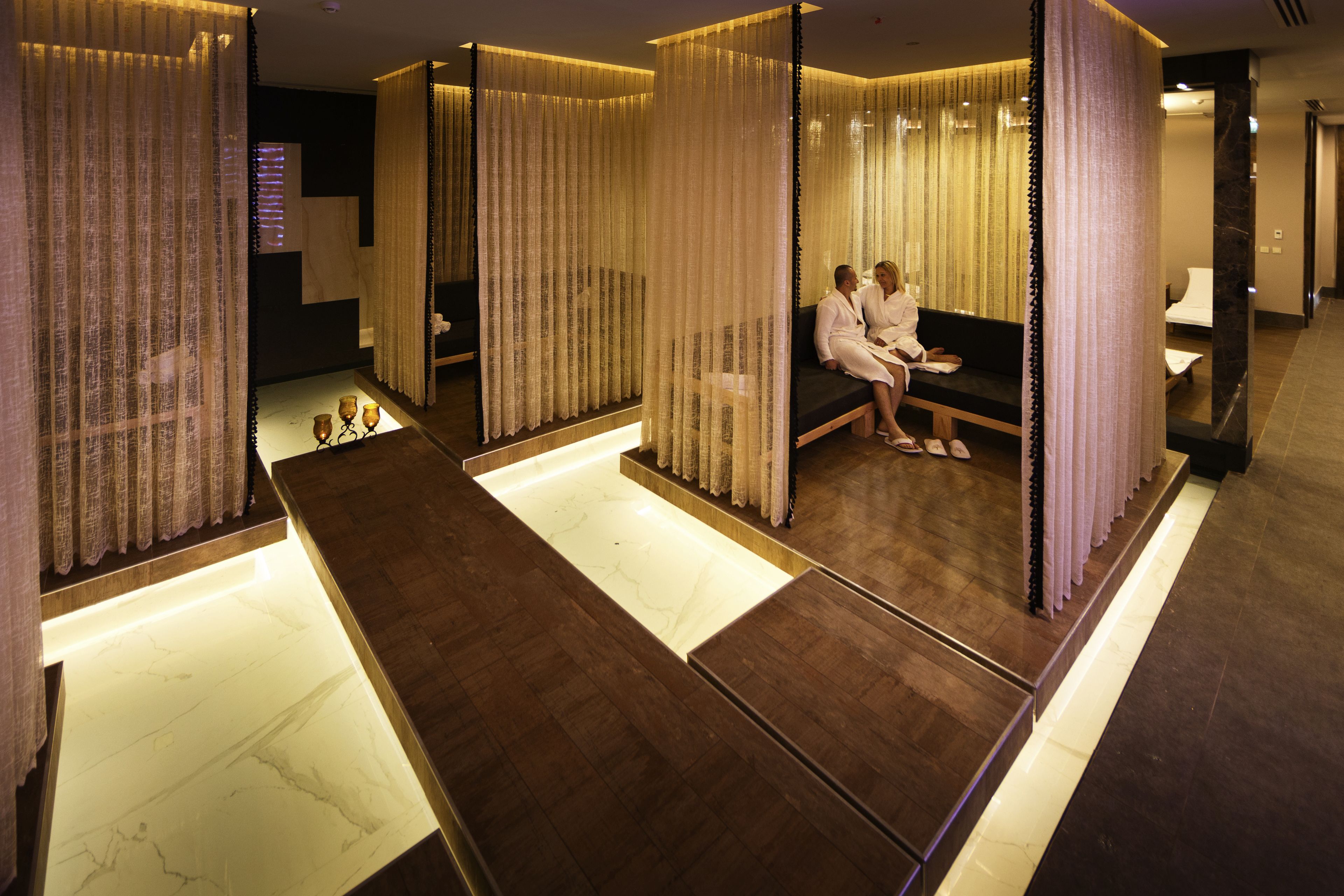 Un área de spa con zona de estar, suelo de madera y suelo de baldosas de mármol.
