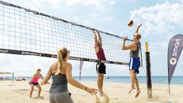 A beach volleyball game with players in action, a net, and beach volleyball equipment.