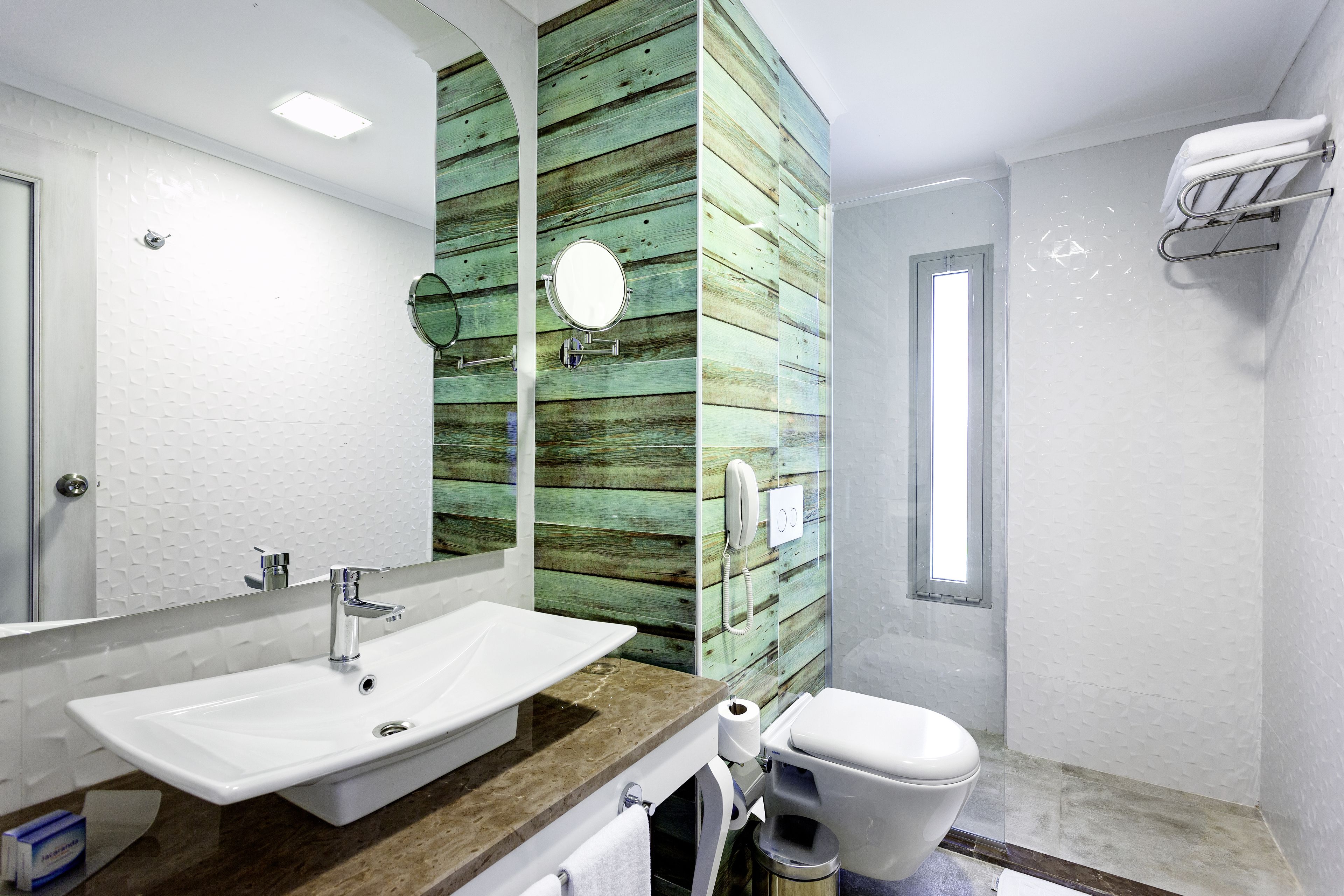 A bathroom with a white sink, a mirror, a toilet, and a towel rack.