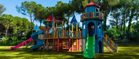 A playground with a slide, climbing structures, and a tower.