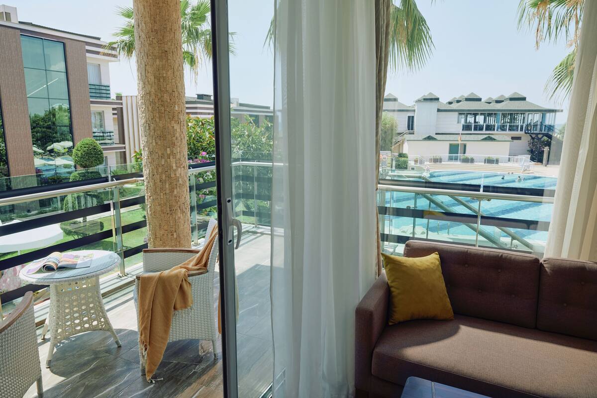 A balcony with a glass door, a brown sofa, and a table with a magazine.