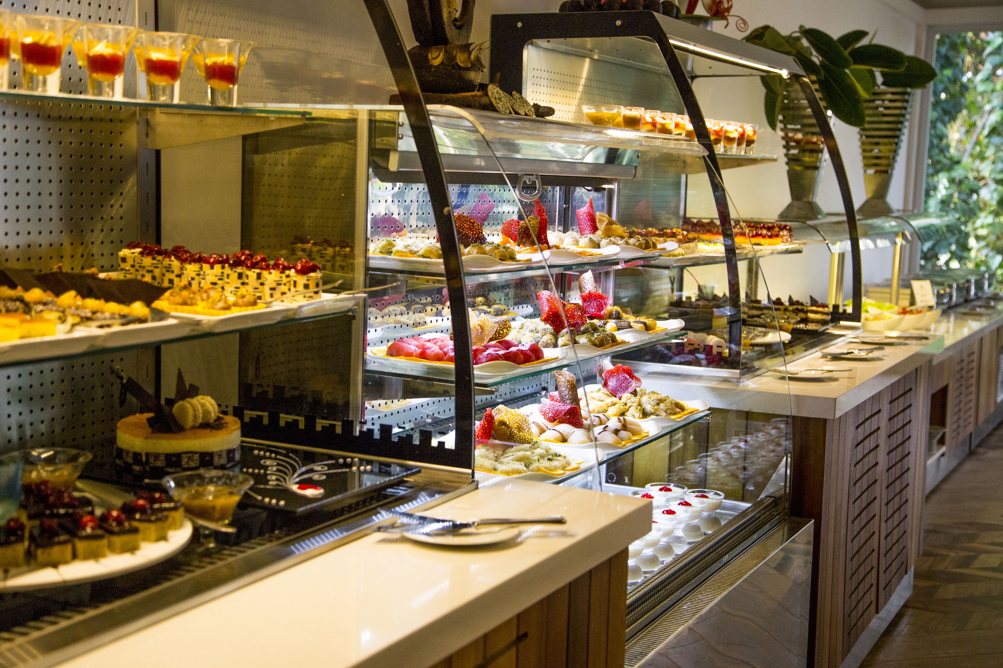 En buffet med forskellige desserter og kager anrettet i glasmontre.