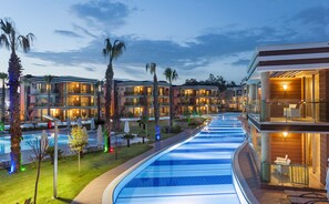 A hotel with multiple balconies, a swimming pool, and palm trees.