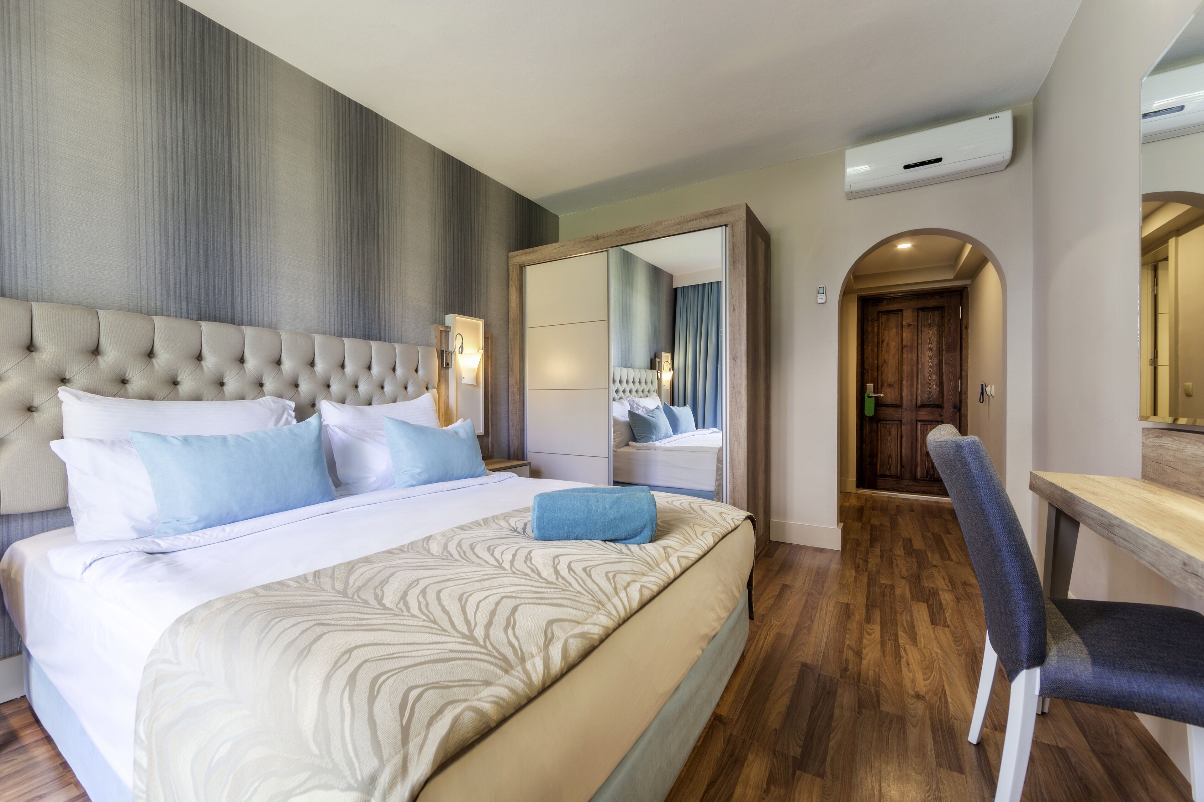 Una camera d'albergo con un letto grande, una scrivania e uno specchio.