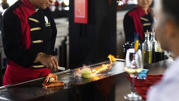 Un cocinero preparando comida en una barra con una parrilla.